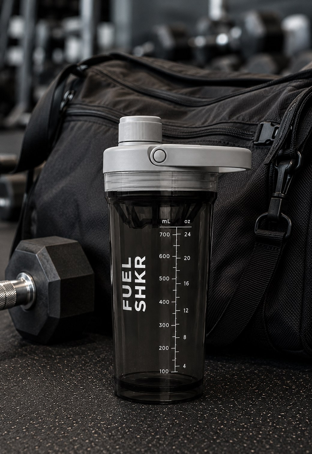 PAKD Fuel Shkr in Black resting against a gym bag with dumbbells